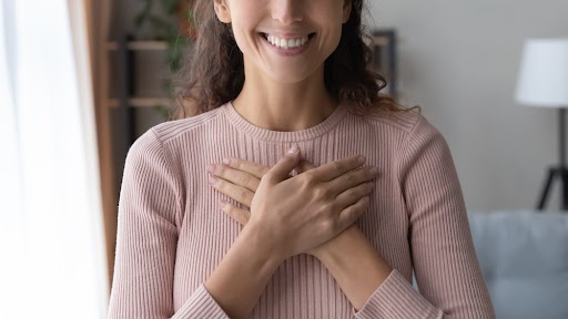 happy sincere female holding folded hands on chest